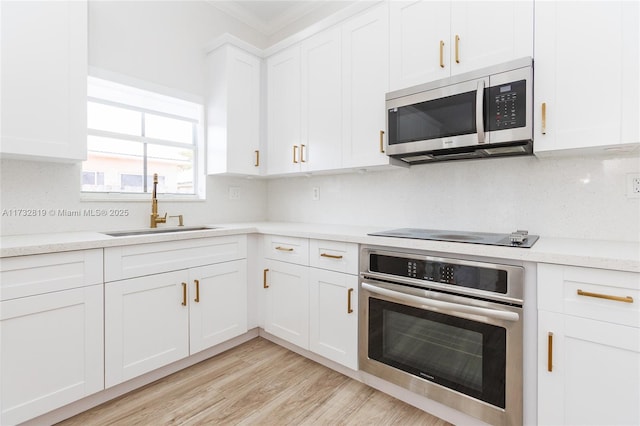 8196 SW 163rd Ct, Miami, FL 33193 - kitchen featuring stainless steel appliances, white cabinetry, ornamental molding, light wood finished floors, and tasteful backsplash