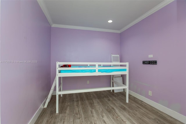 bedroom featuring ornamental molding, baseboards, and wood finished floors