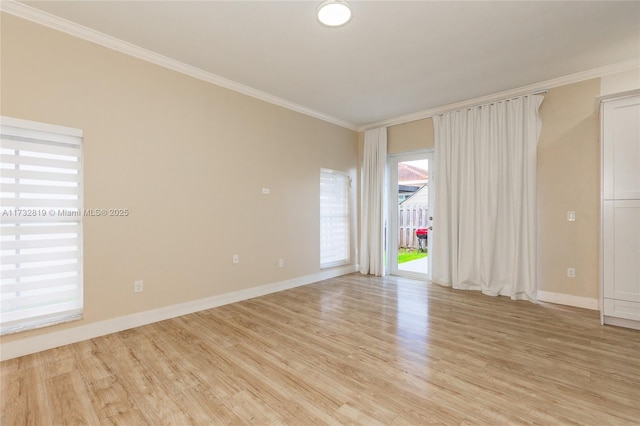 empty room with ornamental molding, light wood-style flooring, and baseboards