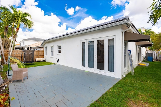 rear view of house featuring a yard, a patio, fence, and stucco siding