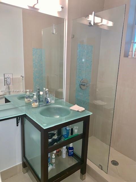 bathroom with a tile shower, sink, and tile patterned flooring