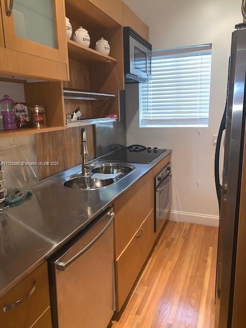 kitchen with stainless steel appliances, sink, and light hardwood / wood-style flooring