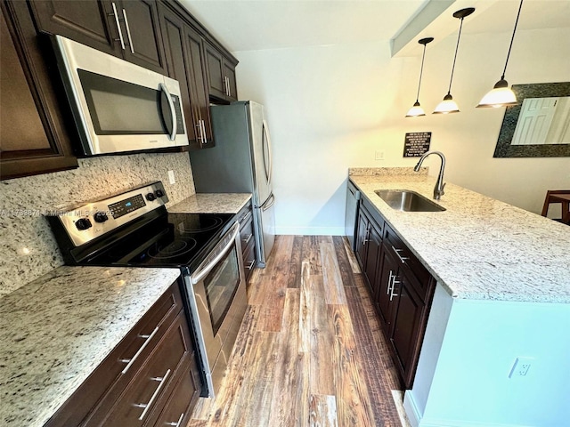 kitchen featuring pendant lighting, sink, appliances with stainless steel finishes, backsplash, and light stone counters