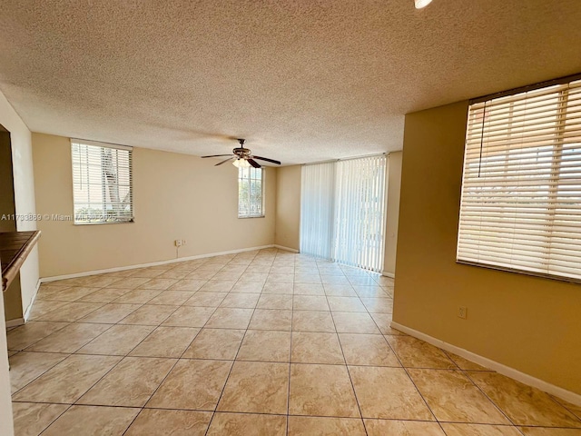 empty room featuring light tile patterned flooring, ceiling fan, and a textured ceiling