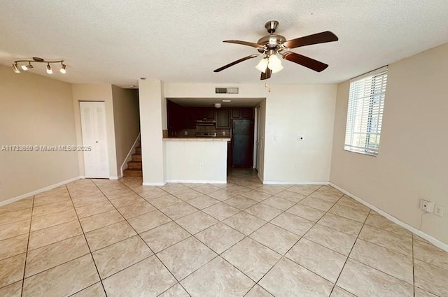 spare room with ceiling fan, a textured ceiling, and light tile patterned floors