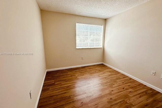 unfurnished room featuring wood-type flooring and a textured ceiling