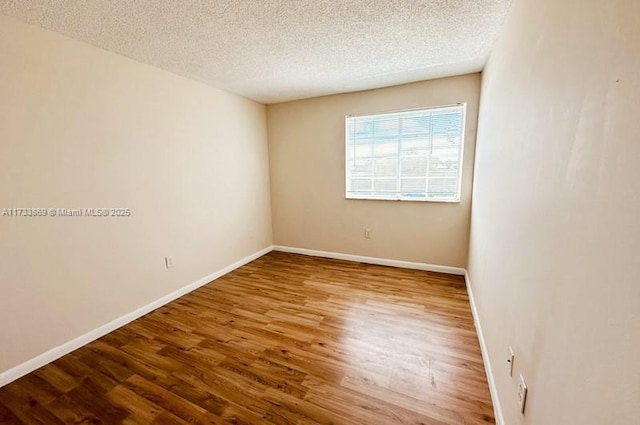 unfurnished room with wood-type flooring and a textured ceiling