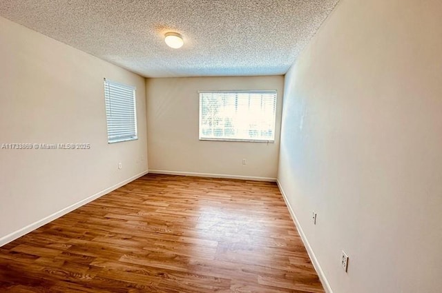 unfurnished room featuring hardwood / wood-style flooring and a textured ceiling