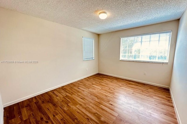 spare room featuring a textured ceiling and light hardwood / wood-style flooring