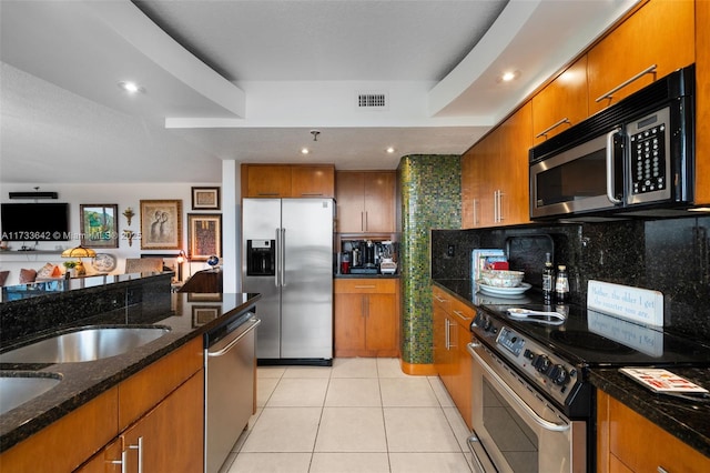 kitchen with light tile patterned flooring, appliances with stainless steel finishes, decorative backsplash, and dark stone countertops