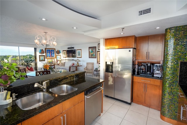 kitchen featuring light tile patterned flooring, sink, dark stone countertops, hanging light fixtures, and stainless steel appliances