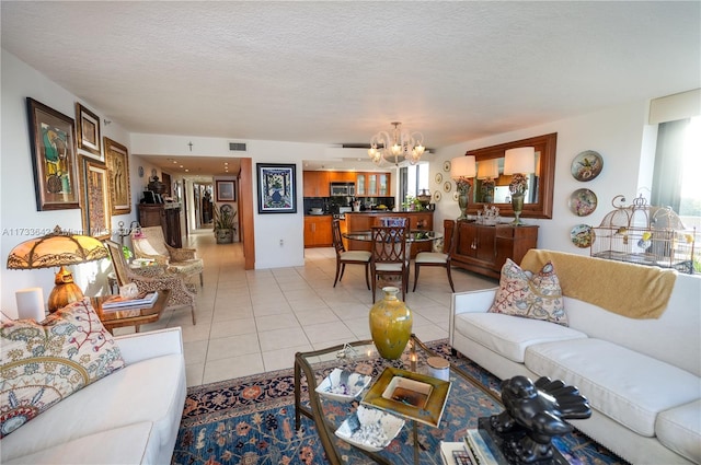 living room featuring light tile patterned flooring, an inviting chandelier, and a textured ceiling