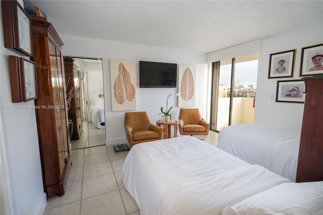 bedroom featuring a closet, a textured ceiling, and light tile patterned flooring