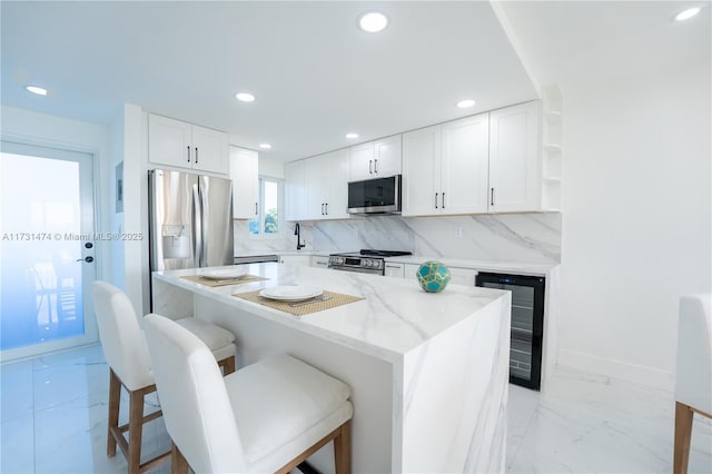 kitchen featuring white cabinetry, stainless steel appliances, a center island, wine cooler, and a kitchen bar