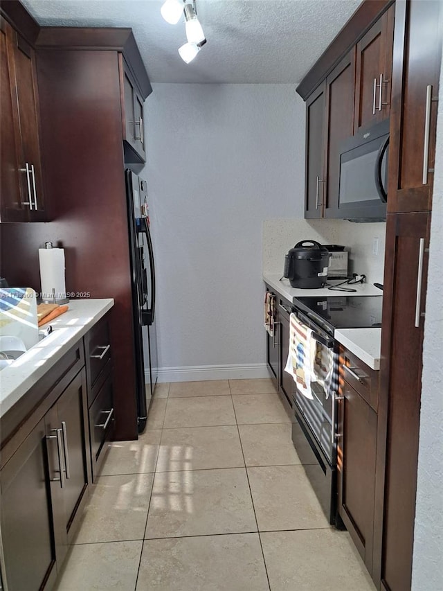 kitchen with light tile patterned floors, dark brown cabinets, and black appliances