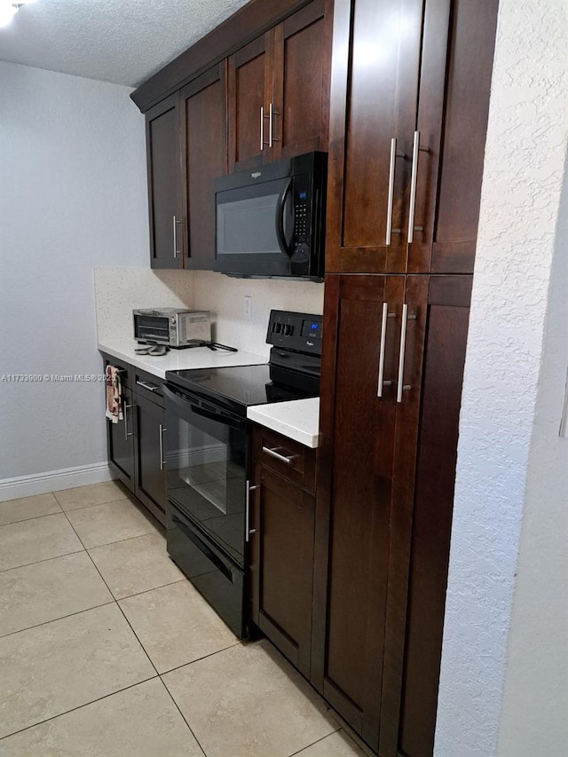 kitchen with light tile patterned floors, a textured ceiling, and black appliances