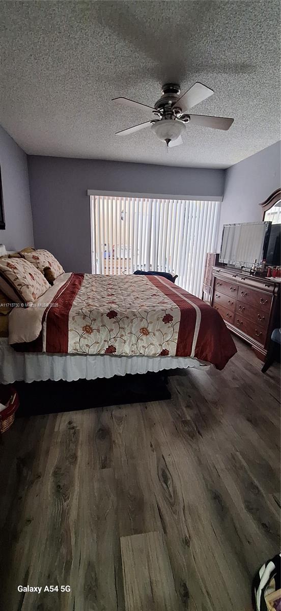 bedroom with hardwood / wood-style floors, a textured ceiling, and ceiling fan