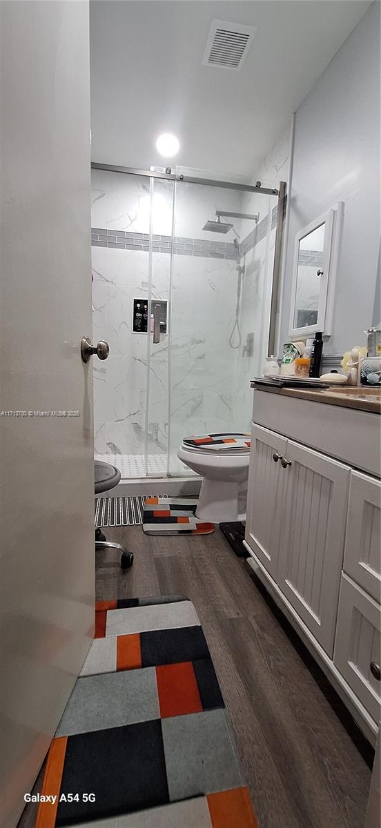 bathroom featuring vanity, toilet, an enclosed shower, and hardwood / wood-style floors