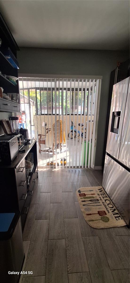 interior space with hardwood / wood-style floors, a healthy amount of sunlight, and stainless steel refrigerator with ice dispenser