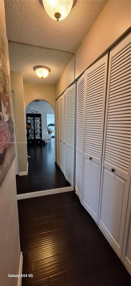 hall with dark wood-type flooring and a textured ceiling