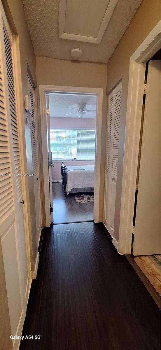 hall with dark hardwood / wood-style flooring and a textured ceiling