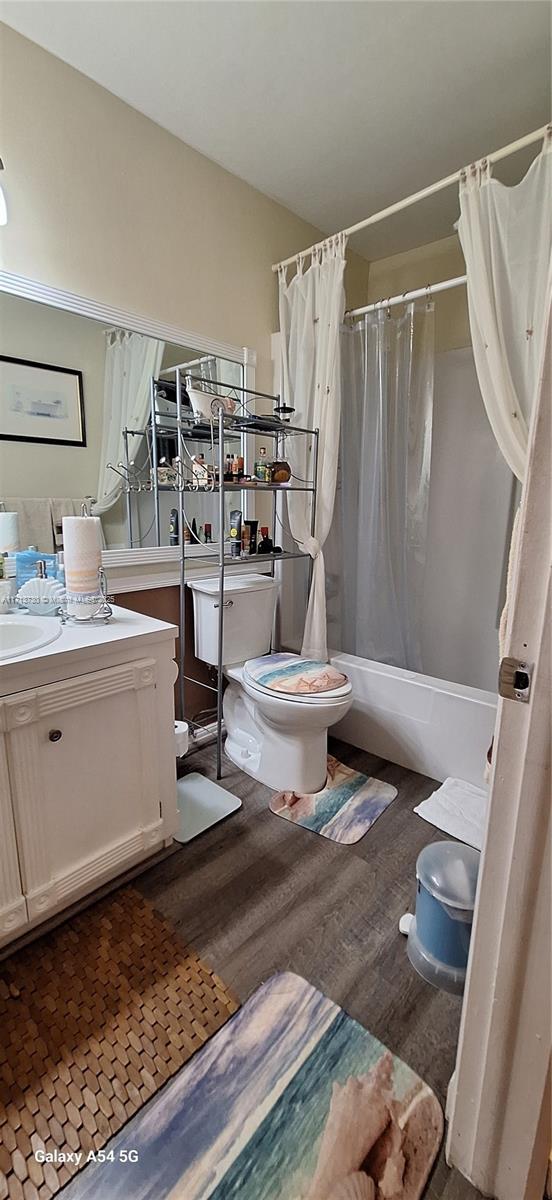 full bathroom featuring shower / tub combo with curtain, vanity, wood-type flooring, and toilet