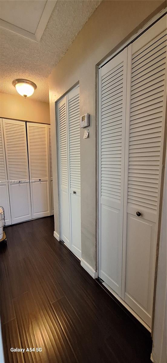 corridor with dark wood-type flooring and a textured ceiling