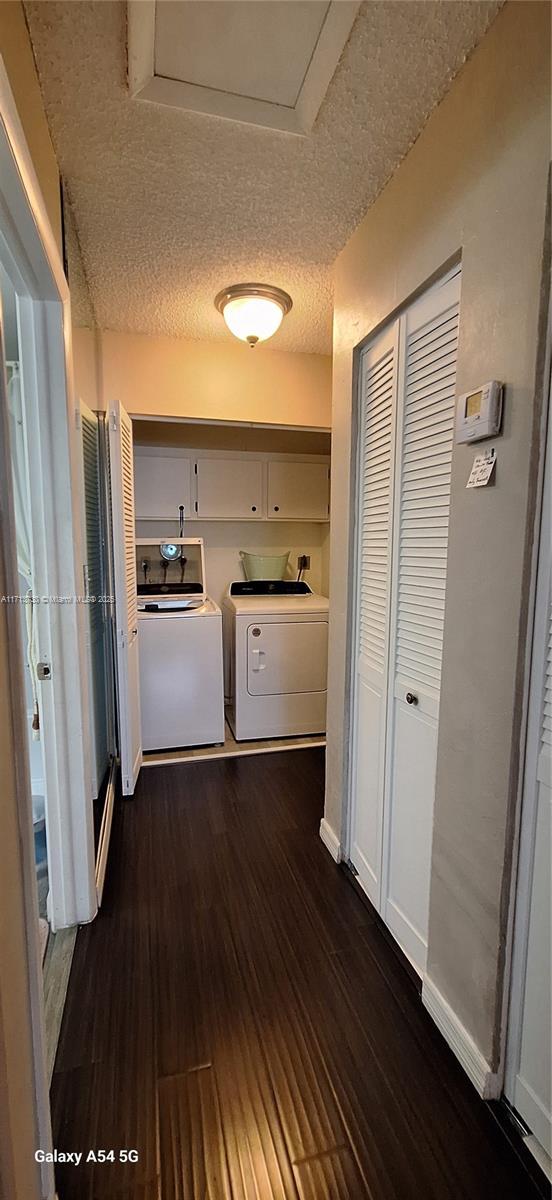 hallway featuring dark hardwood / wood-style flooring, a textured ceiling, and washer and clothes dryer