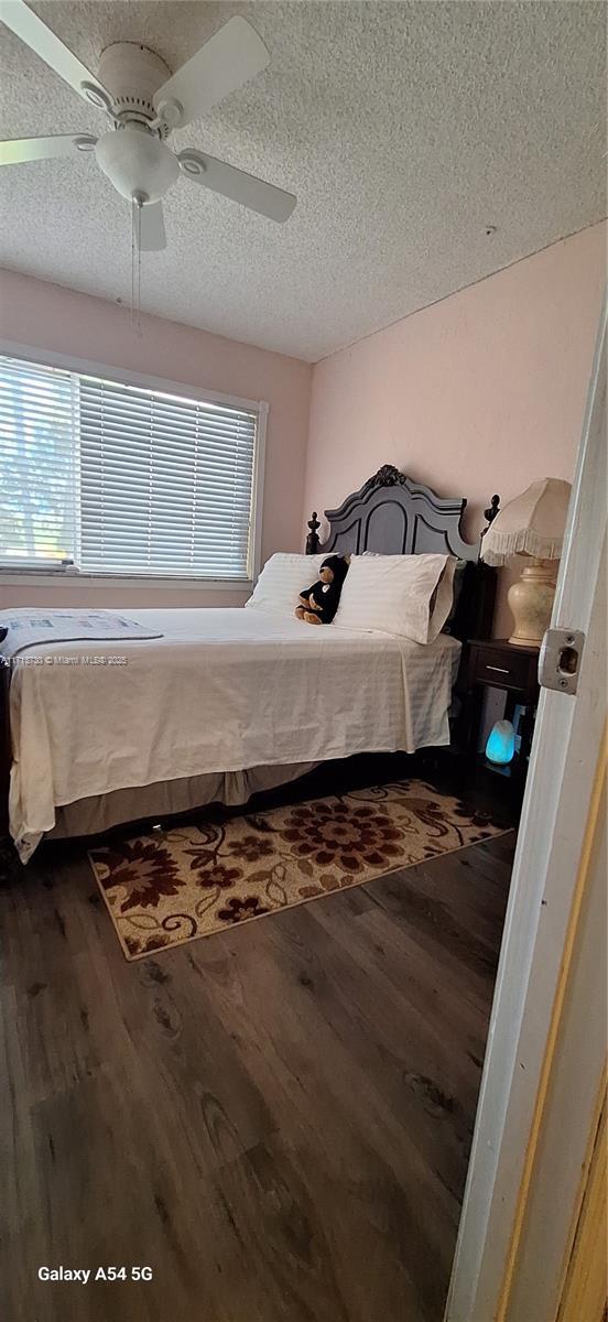 bedroom with ceiling fan, dark hardwood / wood-style floors, and a textured ceiling