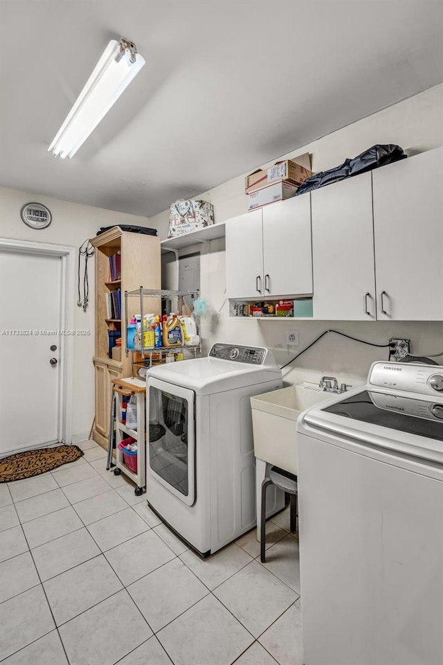 clothes washing area featuring light tile patterned floors, independent washer and dryer, a sink, and cabinet space