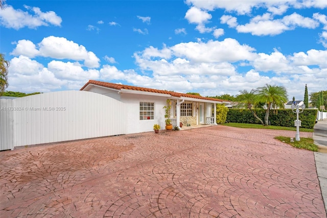 mediterranean / spanish-style house with stucco siding, fence, and a tiled roof