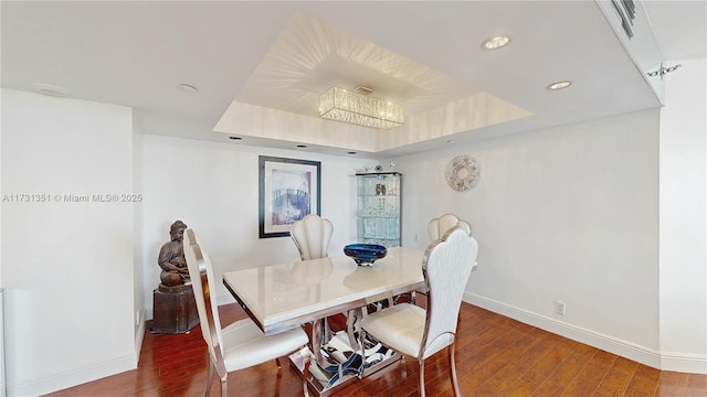 dining area with hardwood / wood-style flooring and a tray ceiling