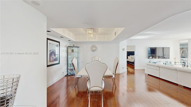 dining room featuring hardwood / wood-style flooring, a tray ceiling, and sink