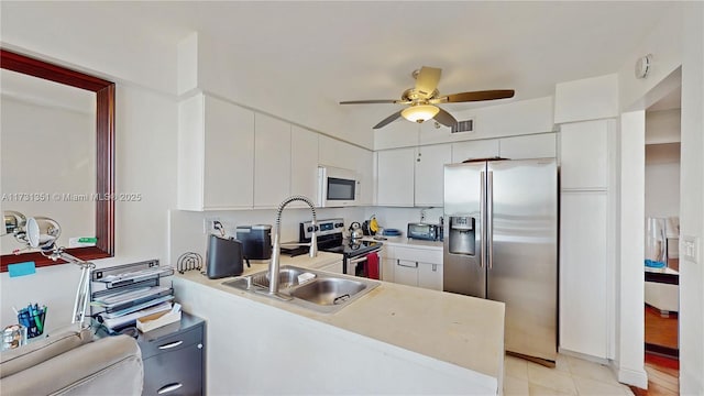 kitchen with ceiling fan, stainless steel appliances, white cabinets, light tile patterned flooring, and kitchen peninsula