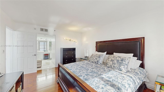 bedroom with ensuite bath and wood-type flooring