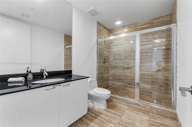 bathroom featuring vanity, a shower with shower door, and toilet