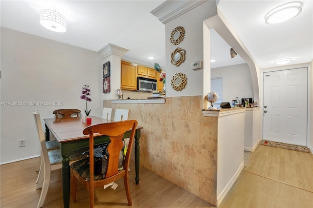 dining area with tile walls and light hardwood / wood-style floors