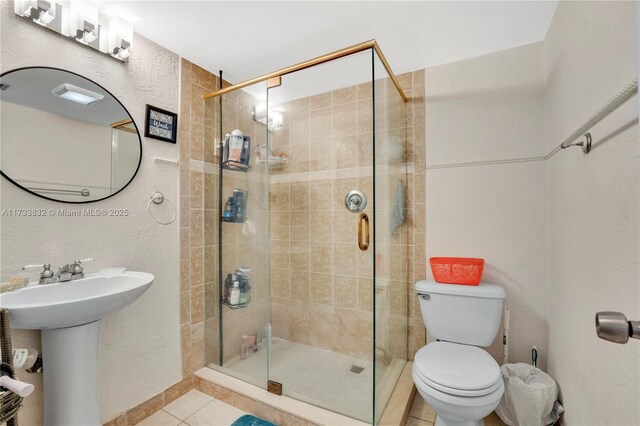 bathroom with sink, toilet, a shower with shower door, and tile patterned flooring