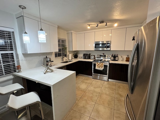 kitchen with white cabinetry, hanging light fixtures, appliances with stainless steel finishes, a kitchen breakfast bar, and kitchen peninsula