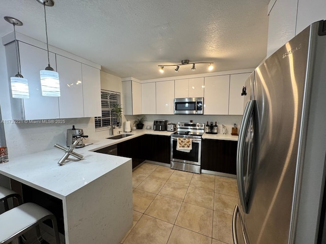 kitchen with white cabinetry, a textured ceiling, appliances with stainless steel finishes, kitchen peninsula, and pendant lighting