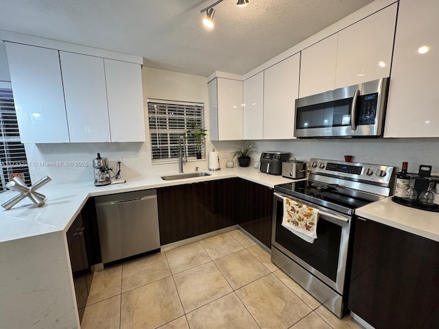 kitchen featuring stainless steel appliances, sink, white cabinets, and a textured ceiling