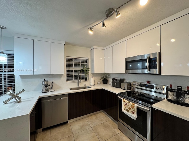 kitchen with dark brown cabinetry, sink, white cabinetry, a textured ceiling, and stainless steel appliances