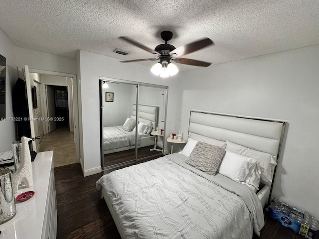 bedroom featuring dark hardwood / wood-style flooring, a textured ceiling, ceiling fan, and a closet