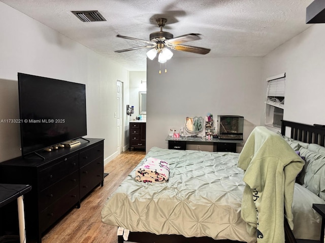 bedroom with a textured ceiling, light hardwood / wood-style flooring, and ceiling fan