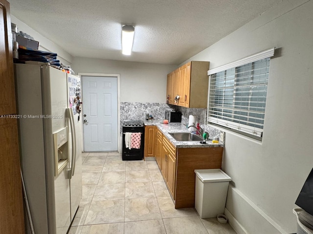 kitchen with sink, black range with gas cooktop, backsplash, white refrigerator with ice dispenser, and a textured ceiling