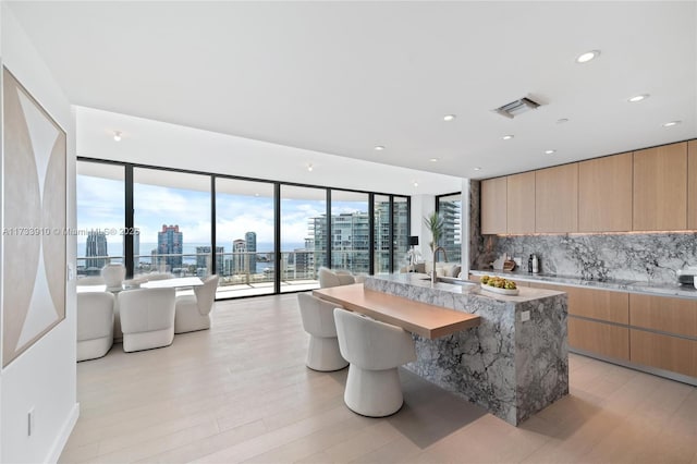 kitchen with a city view, visible vents, tasteful backsplash, an island with sink, and modern cabinets