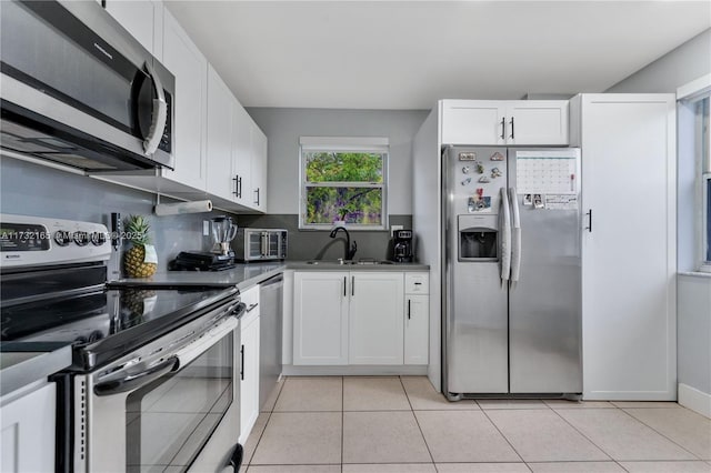 kitchen featuring light tile patterned flooring, stainless steel appliances, sink, and white cabinets