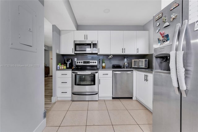 kitchen featuring backsplash, stainless steel appliances, light tile patterned floors, and white cabinets