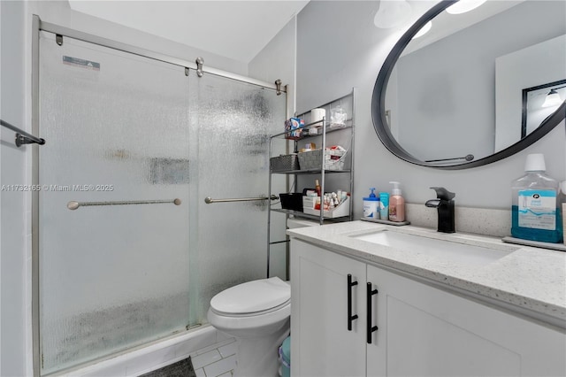 bathroom with a shower with door, vanity, tile patterned floors, and toilet