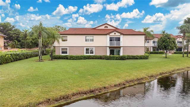 back of house with a yard and a water view